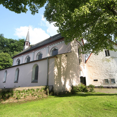 Kloster Seligenthal Historische Kirche in Siegburg, umgeben von Grünflächen und Bäumen, bei strahlendem Sonnenschein.