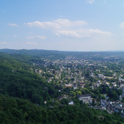 Ausblick unterhalb des Drachenfels über Rhöndorf und Bad Honnef Luftaufnahme einer grünen, waldreichen Landschaft mit einer Stadt am Ufer eines Flusses.