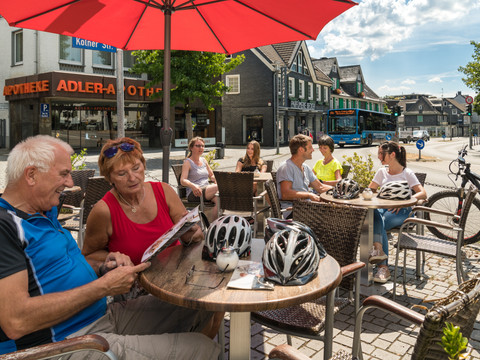 Pause mit dem FahrradBus  Personen genießen an einem sonnigen Tag in einem Straßencafé in Wermelskirchen ihre Zeit.