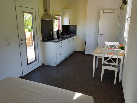 Büschem's Box Heller Raum mit moderner Küchenzeile, Esstisch und Tür zu Terrasse. Schlicht und einladend gestaltet.