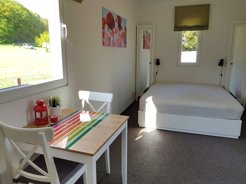 Büschem's Box Helles Schlafzimmer mit Doppelbett, kleinem Esstisch und bunten Dekorationen. Fenster mit Naturblick.