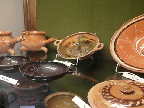 Verschiedene historische Keramikschalen und Töpfe in einem Museum ausgestellt.