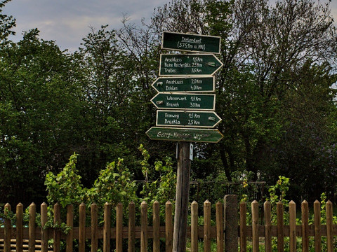 Wegweiser vor Holzzaun mit Richtungsangaben zu umliegenden Orten in Dörtendorf.Signpost in front of wooden fence with directions to surrounding villages in Dörtendorf.Směrovka před dřevěným plotem se směrovkami do sousedních obcí v Dörtendorfu.Drogowskaz przed drewnianym płotem ze wskazówkami do sąsiednich wiosek w Dörtendorf.Wegwijzer voor houten hek met aanwijzingen naar naburige dorpen in Dörtendorf.Cartello davanti alla recinzione in legno con indicazioni per i villaggi vicini a Dörtendorf.