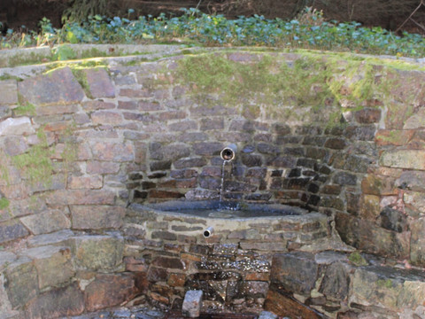 Quellbrunnen aus Naturstein, umgeben von Wald, mit moosbewachsenen Steinen.Spring fountain made of natural stone, surrounded by forest, with moss-covered stones.Pramenitá fontána z přírodního kamene, obklopená lesem, s kameny porostlými mechem.Fontanna źródlana wykonana z naturalnego kamienia, otoczona lasem, z kamieniami pokrytymi mchem.Bronfontein van natuursteen, omgeven door bos, met met mos bedekte stenen.Fontana sorgiva in pietra naturale, circondata dal bosco, con pietre ricoperte di muschio.