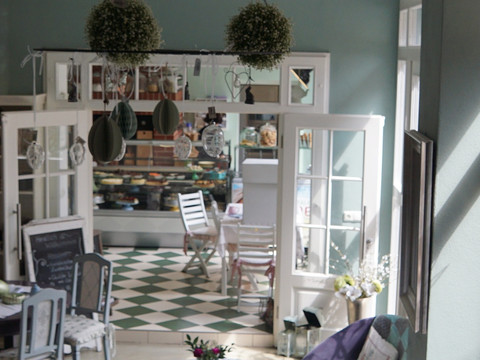 Bright room of a patisserie with vintage furniture and a counter full of baked goods.