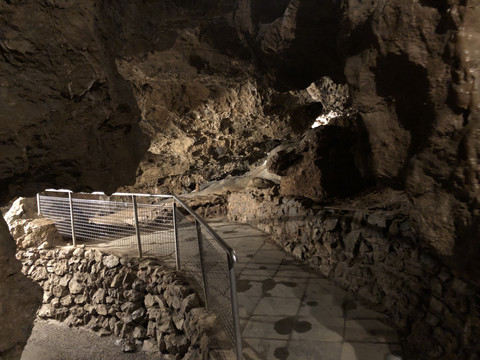 Wiehler Tropfsteinhöhle Naturhöhle mit steinigen Wänden, durchzogen von einem schmalen, gepflasterten Weg mit Geländer.