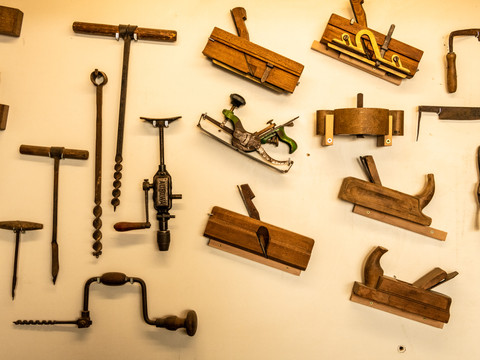 Technik- und Bauernmuseum Alte Holzbearbeitungswerkzeuge hängen geordnet an einer hellen Wand.