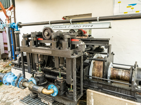 Technik und-Bauernmuseum Maschinelle Apparatur von Lambach L-380 1914 in einem Innenhof, umgeben von Rohren und Wänden.