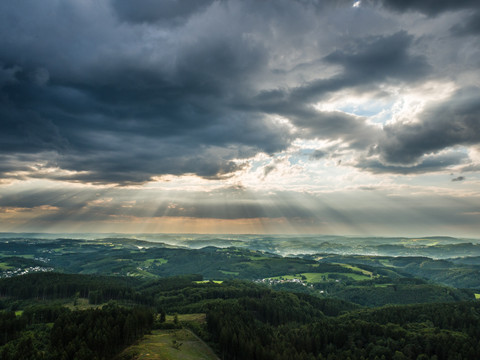 Reichshof Blockhaus Landschaftspanorama von Reichshof mit dramatischen Wolken und Sonnenstrahlen über grünen Hügeln.