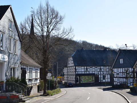 Fachwerkdorf Holpe Fachwerkhäuser säumen eine ruhige Dorfstraße in Morsbach mit kahlen Bäumen im Hintergrund.