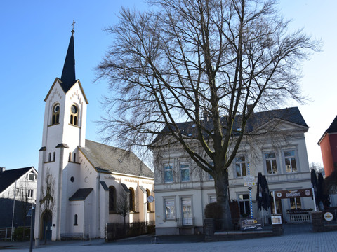 Ev. Kirche Am Markt  <p>Weiße Kirche neben Altbau und Baum, blauer Himmel, in Wipperfürth. Hauptstraße im Vordergrund.</p>