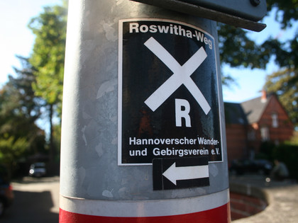 Markierung Roswithaweg Markierung des Roswithawegs an einem Pfosten mit klar erkennbaren Symbolen und Richtungspfeil.