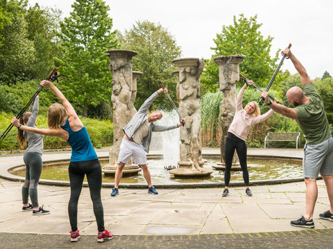 Kurpark Nümbrecht Nordic-Walking-Gruppe bei Training vor einer Skulpturenbrunnen-Anlage im Freien bei bewölktem Wetter.