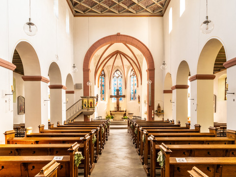 Innenstadt <p>Innenansicht einer Kirche mit Holzbänken und buntem Glasfenster im Hintergrund.</p>