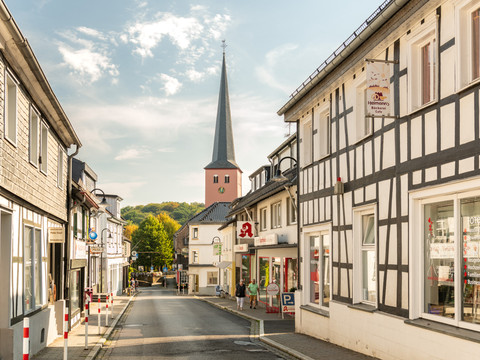 Innenstadt <p>Eine malerische Straße in Much, gesäumt von Fachwerkhäusern, mit Kirchturm im Hintergrund.</p>