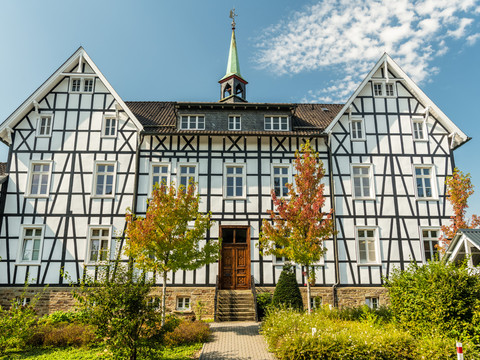 Kneipp-Vitalpark <p>Fachwerkhaus mit grünem Turm und blauen Himmel im Hintergrund; flankiert von bunten Herbstbäumen.</p>