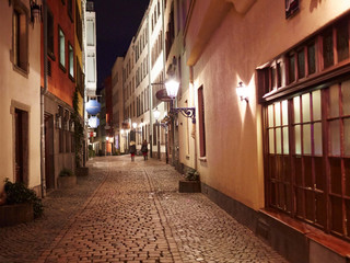 Cologne old town Abendstimmung in einer Altstadtgasse von Köln, belebt von zwei Personen auf Kopfsteinpflaster.Evening atmosphere in an old town alley in Cologne, animated by two people on cobblestones.