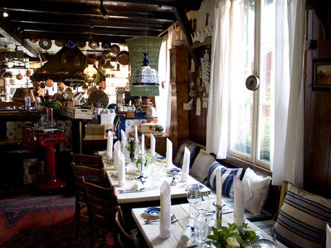 Droeppelminna-restaurant-Bergisch-Gladbach-Herrenstrunden-Joel-Schramm.jpg Gemütliches, traditionelles Gasthausinterieur mit holzvertäfelten Wänden, gedeckter Tisch, warm erleuchtet.