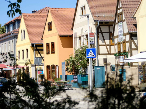 Row of colorful half-timbered houses in Altkötzschenbroda, Radebeul, with café and pedestrian zone in the sunshine.