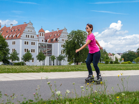 021 - Zwickau - Muldeparadies, Schloss Osterstein - © Kultour Z.jpg Eine Frau rollt auf Inlineskates auf einem Weg, vor dem Schloss Osterstein.