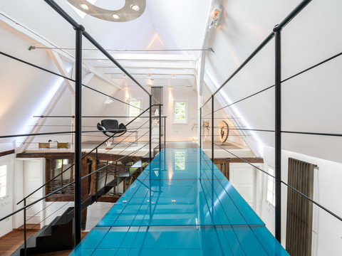 Treppenhaus im Obergeschoss Modernes Dachgeschoss mit Glassteg und stilvoller Inneneinrichtung, weißen Wänden, Holzbalken.