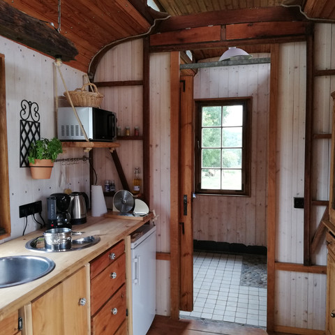 Innenansicht Gemütliches Kücheninterieur in einem Holzwagen mit Fenster, Spüle, Herdplatte und rustikaler Einrichtung.