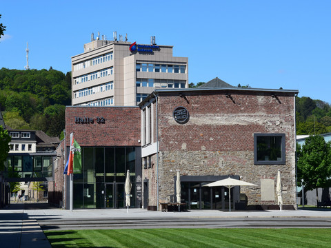 Steinmüllergelände Gummersbacher Kulturzentrum "Halle 32" bei strahlendem Sonnenschein vor grün bewachsenem Hügel.