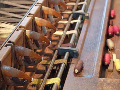 Traditionelle Webmaschine mit Spulen in verschiedenen Farben auf einer Holzoberfläche.Traditional weaving machine with bobbins in different colors on a wooden surface.Tradiční tkalcovský stav s různobarevnými cívkami na dřevěném povrchu.Tradycyjna maszyna tkacka z różnokolorowymi szpulkami na drewnianej powierzchni.Traditionele weefmachine met klosjes in verschillende kleuren op een houten oppervlak.Macchina per tessere tradizionale con bobine di diversi colori su una superficie di legno.