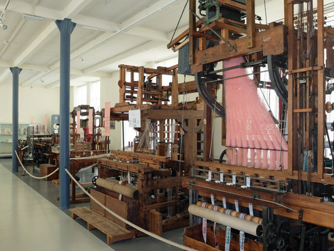 Historische Webstühle in einem Industriemuseum mit Ausstellungsstücken in einem hellen Raum.Historic looms in an industrial museum with exhibits in a bright room.Historické krosny v průmyslovém muzeu s exponáty ve světlé místnosti.Historyczne krosna w muzeum przemysłowym z eksponatami w jasnym pomieszczeniu.Historische weefgetouwen in een industrieel museum met tentoonstellingen in een lichte kamer.Telai storici in un museo industriale con esposizioni in una sala luminosa.