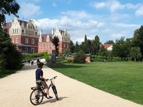 Fürst Pückler Park, Bad Muskau Ein Junge mit Fahrrad auf einem Weg im Fürst Pückler Park vor einem Herrenhaus.A boy with a bicycle on a path in Fürst Pückler Park in front of a manor house.Chlapec s kolem na stezce v parku Fürst Pückler před zámkem.Chłopiec z rowerem na ścieżce w parku Fürsta Pücklera przed dworem.Een jongen met een fiets op een pad in het Fürst Pückler Park voor een landhuis.Un ragazzo con la bicicletta su un sentiero del parco Fürst Pückler, di fronte a una casa padronale.