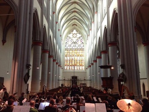 Altenberg Orchesterperspektive Musiker proben in einer großen gotischen Kirche mit beeindruckenden Buntglasfenstern und hohen Säulen.