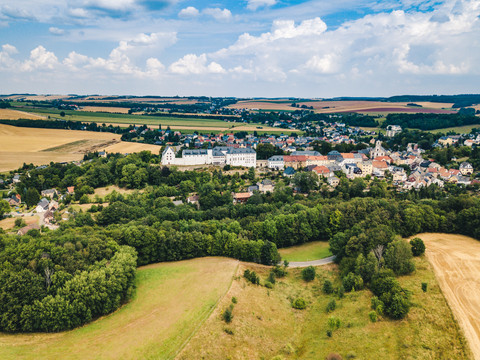 Aerial view of Wildenfels Castle and town surrounded by green countryside and fields.