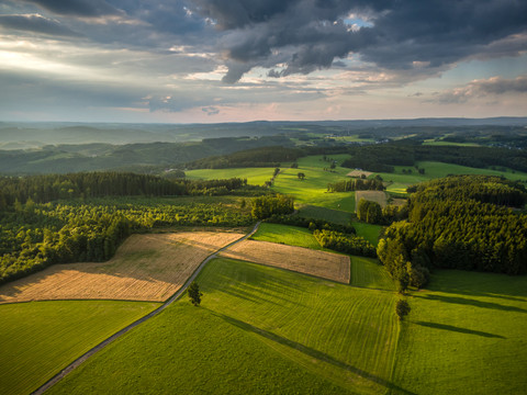 Reichshof Blockhaus <p>Weite, grüne Landschaft mit Feldern, Wäldern und sanften Hügeln unter wolkigem Himmel im Abendlicht.</p>