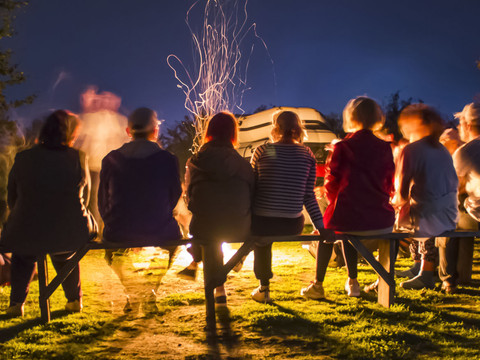 Wanderer am Lagerfeuer Eine Gruppe von Menschen sitzt abends um ein prasselndes Lagerfeuer im Freien.
