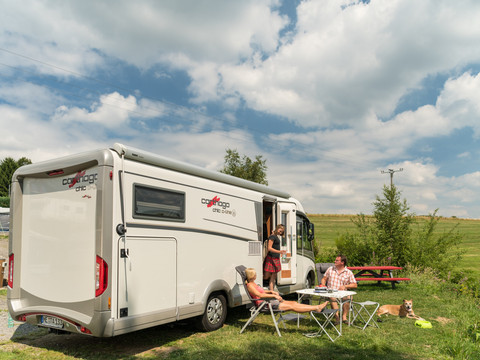 Campingpark im Bergischen Land <p>Ein Wohnmobil steht auf einem Rasenplatz, Menschen genießen Sonne und Entspannung im Freien.</p>