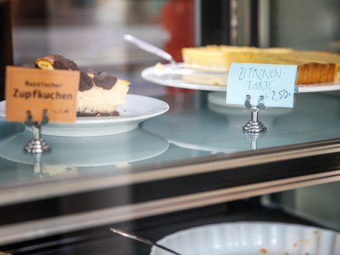 Aufnahme der köstlichen Kuchen, die sich mitsamt Beschilderung in der Glas-Vitrine des Jimmy Orpheus-Café befinden, restaurant, cafe, kulinarik, genuss, freizeit