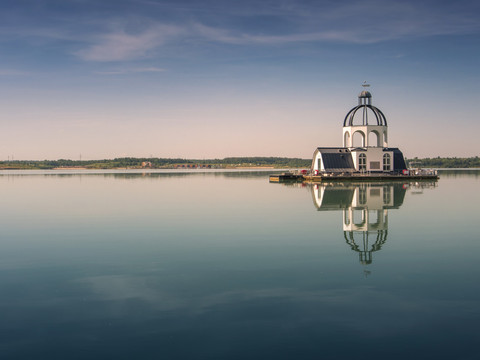 Die VINETA inmitten des Störmthaler Sees im Leipzig Neuseenland ähnelt einem schwimmenden, kirchenähnlichen Gebäude und spiegelt sich bei untergehender Sonne im Wasser