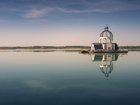 VINETA na jeziorze Störmthaler See w wieczornym świetle – region Leipziger Neuseenland Pływający kościół VINETA, położony pośrodku jeziora Störmthaler See w regionie Leipzig Neuseenland, odbija się w wodzie w promieniach zachodzącego słońca; region Lipsk, miejsce wycieczek