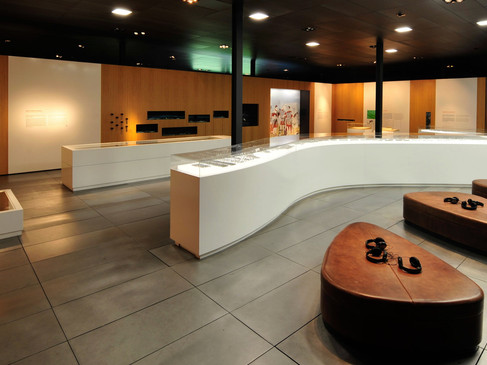 Moderne Museumsausstellung mit informativem Wandpanel, Glasvitrinen und bequemen Sitzgelegenheiten.