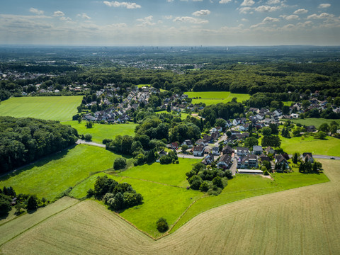 Odenthal <p>Panorama von Odenthal: grüne Felder, Wald und verstreute Häuser vor einem bewölkten Himmel.</p>