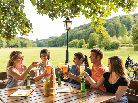 Biergarten in Altenberg Menschen genießen geselliges Beisammensein bei Getränken im Grünen unter Bäumen.