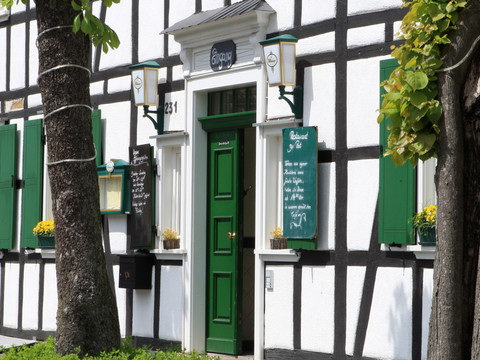 Hotel-Restaurant "Zur Post"  <p>Fachwerkhaus mit grüner Tür und Schildern, umgeben von Bäumen und Blumen in Odenthal.</p>