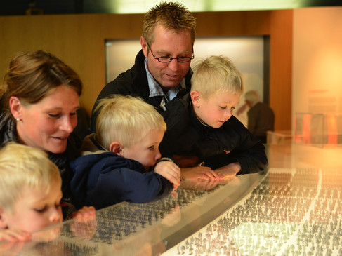 Eine Familie blickt mit Begeisterung auf eine Ausstellung im Museum Kalkriese.