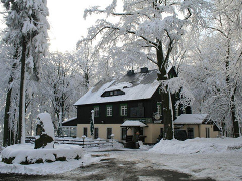 Excursie restaurant op de Ungerberg Schneebedecktes Gebäude im Wald, umgeben von verschneiten Bäumen, mit ruhiger Winteratmosphäre.