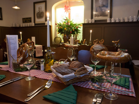 Officierskantine Restaurant Vesting Königstein Festlich gedeckter Tisch in einem bayerischen Restaurant mit Brezeln auf Gläsern, Kerzenlicht, Brot und Tannenzweigen auf rot-weiß kariertem Tischtuch.Festively laid table in a Bavarian restaurant with pretzels on glasses, candlelight, bread and fir branches on a red and white checkered tablecloth.Slavnostně prostřený stůl v bavorské restauraci s preclíky na sklenicích, světlem svíček, chlebem a jedlovými větvičkami na červenobílém kostkovaném ubrusu.Odświętnie nakryty stół w bawarskiej restauracji z preclami na szklankach, blaskiem świec, chlebem i gałązkami jodły na obrusie w czerwono-białą kratę.Feestelijk gedekte tafel in een Beiers restaurant met pretzels op glazen, kaarslicht, brood en sparrentakken op een rood en wit geblokt tafelkleed.Tavola imbandita a festa in un ristorante bavarese con pretzel sui bicchieri, lume di candela, pane e rami di abete su una tovaglia a scacchi rossi e bianchi.