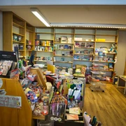 Einblick in die Bücherstube Eine gemütliche Bücherstube mit voll bepackten Regalen, die bunte Bücher und Schreibwaren präsentieren.
