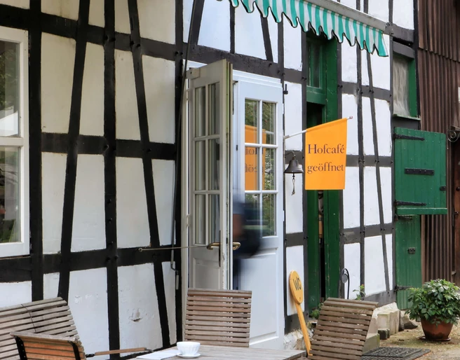 Biohof Hofcafe auf Hof zur Hellen im Windrather Tal be Velbert Traditionelles Fachwerkhaus mit Außenterrasse und geöffnetem Hofcafé im Windrather Tal bei Velbert.