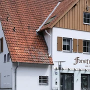 Forstfrieden.jpg Hotel Forstfrieden, zweistöckiges Gebäude mit roten Dachziegeln, liegt in grüner, bewaldeter Umgebung.