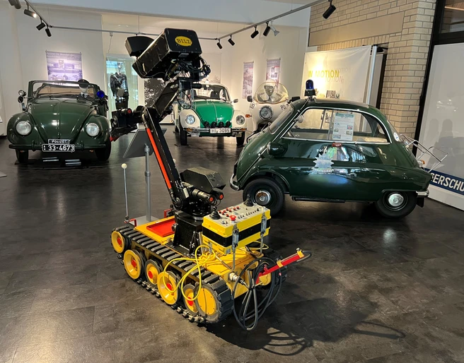 Polizeimuseum Niedersachsen Ein Innenraum des Polizeimuseums Niedersachsen mit historischen Polizeiautos und einem Roboter.