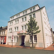 Vierstöckiges Arthotel ANA Fleur im klassischen Stil, umgeben von Bäumen, unter blauem Himmel.